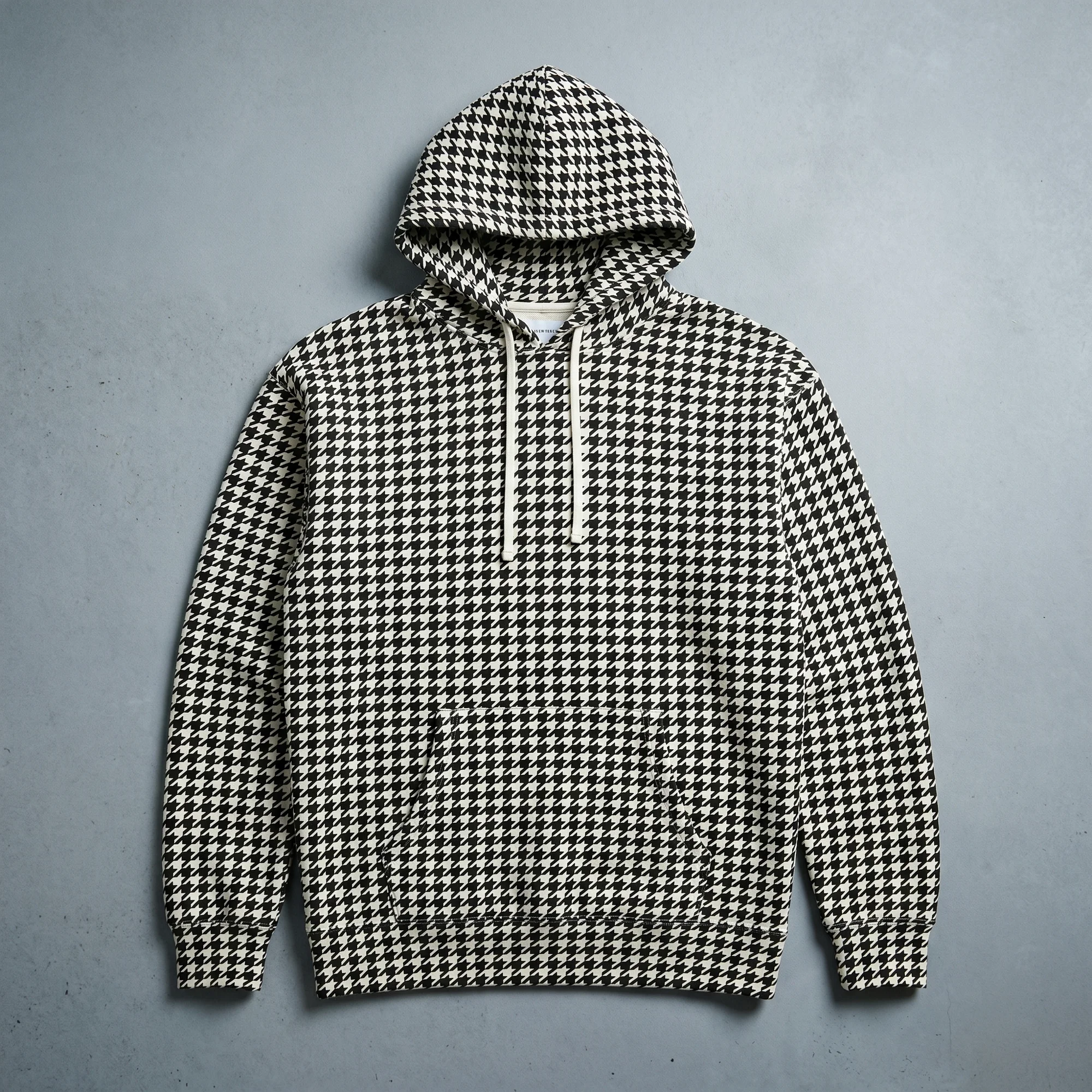 Black and white houndstooth hoodie laid flat, showing the front, hood, and kangaroo pocket