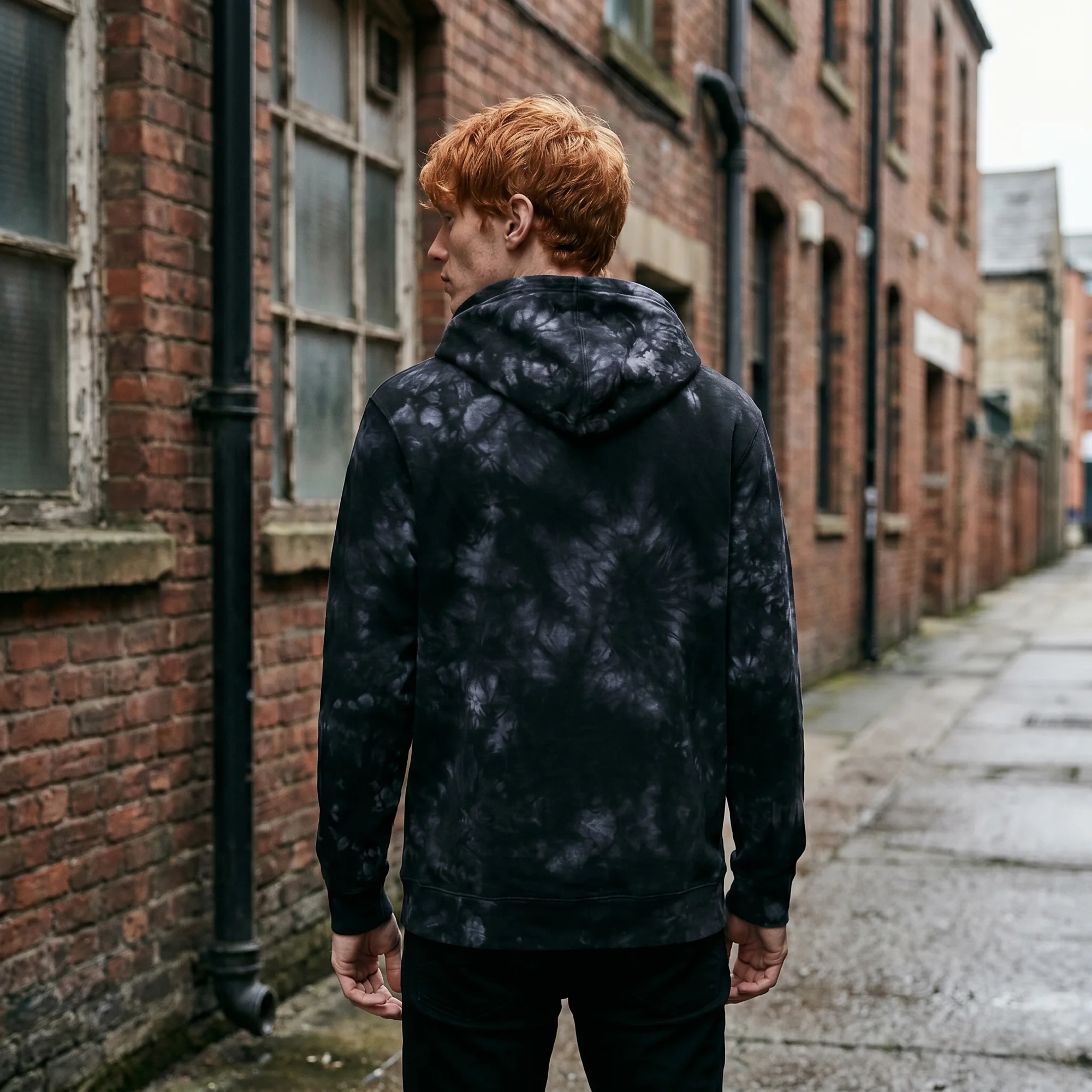 Back view of a man wearing an black tie-dye hoodie, showing the fit and hood