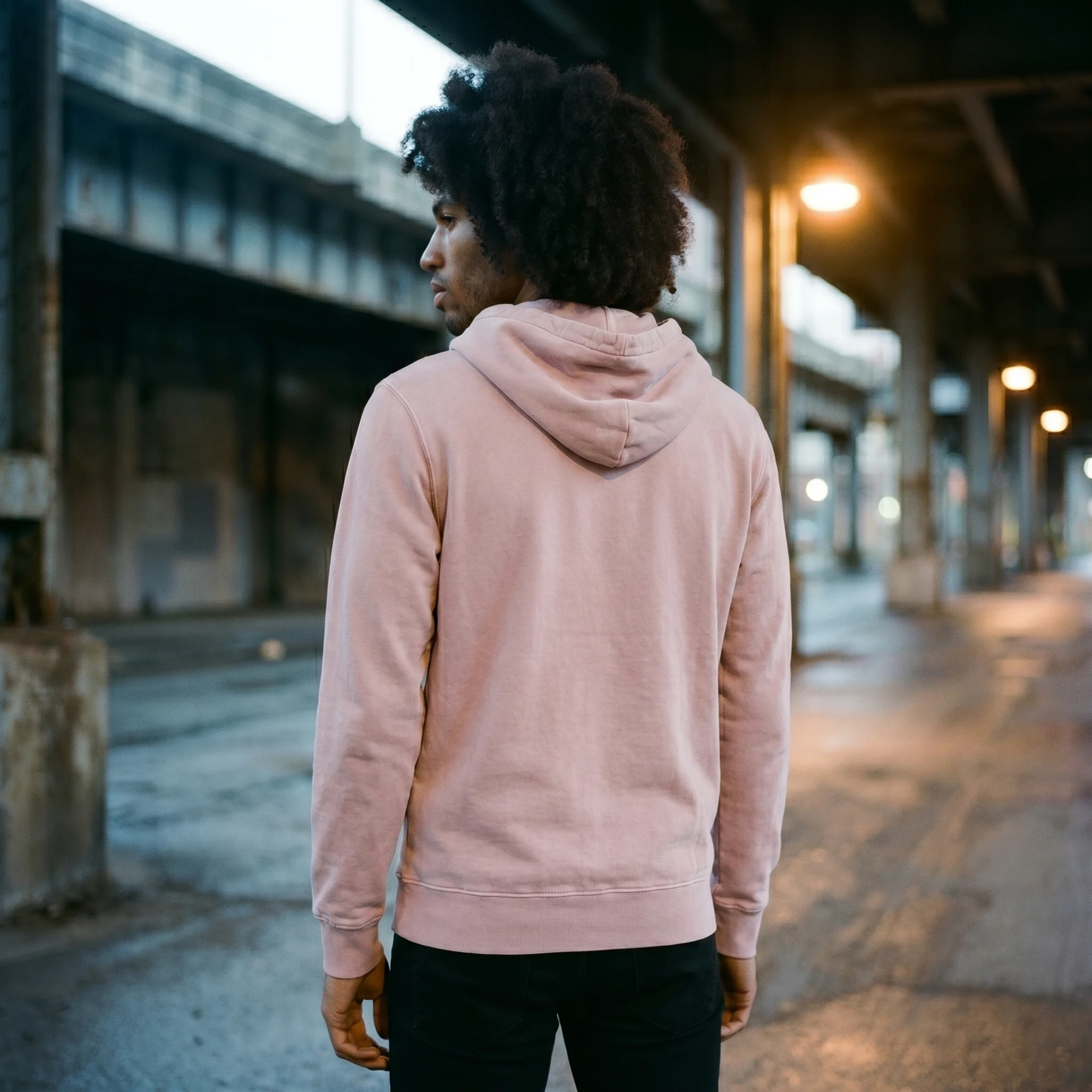 Back view of a man wearing a pink pigment dye hoodie, showing the fit and hood