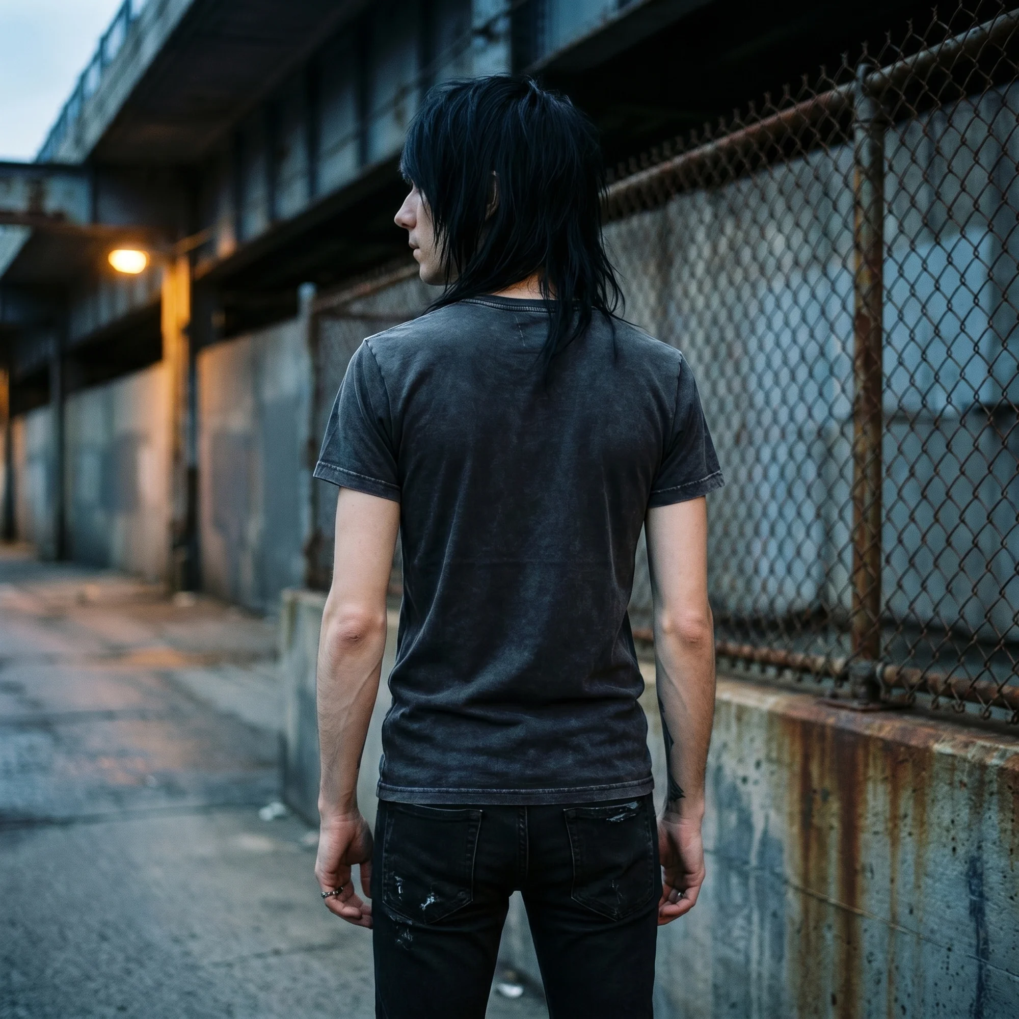 Back view of a man wearing a black vintage wash t-shirt, showing the plain back and fit