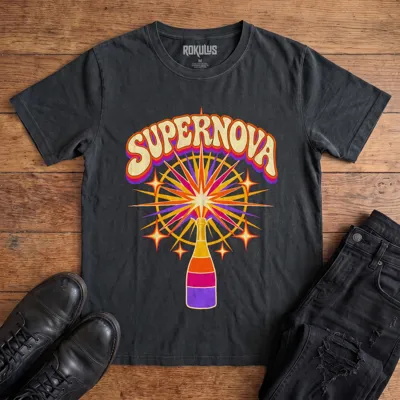 Washed black Rokulus Champagne Supernova vintage graphic tee laid flat on wood with black boots and jeans, front print showing a champagne bottle erupting in a psychedelic sunburst of purple, pink, and orange under groovy “Supernova” lettering