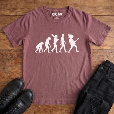 Washed maroon Rokulus Rock Evolution vintage graphic tee laid flat on wood with black boots and jeans, front print showing the evolution chart silhouette ending in a long-haired rocker shredding an electric guitar