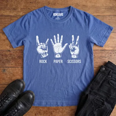 Washed royal blue Rokulus Rock Paper Scissors vintage graphic tee laid flat on wood with black boots and jeans, front print showing three hands in vintage engraving, devil horns for rock, flat palm for paper, peace sign for scissors