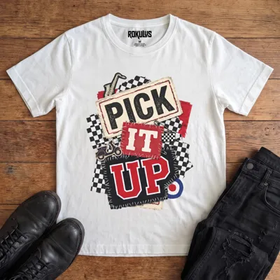 White Rokulus Pick It Up Ska vintage graphic tee laid flat on wood with black boots and jeans, front print showing a 2-tone ska collage with checkerboard, saxophone, scooter, and mod target under stitched "Pick It Up" lettering