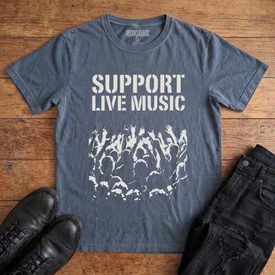 Washed navy Rokulus Support Live Music vintage graphic tee laid flat on wood with black boots and jeans, front print showing "Support Live Music" in stencil type above a silhouetted concert crowd with raised hands