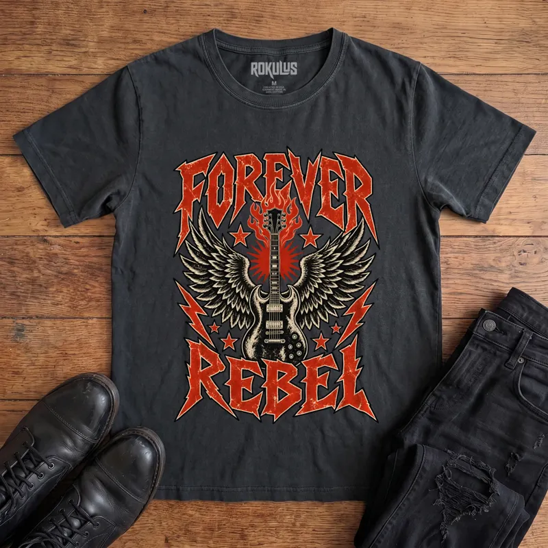 Washed black Rokulus Forever Rebel vintage graphic tee laid flat on wood with black boots and jeans, front print showing a winged electric guitar in flames with lightning bolts and stars under jagged “Forever Rebel” metal lettering