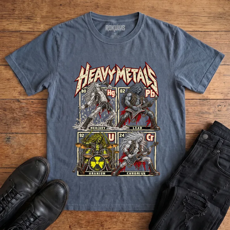 Washed navy Rokulus Heavy Metals vintage graphic tee laid flat on wood with black boots and jeans, front print showing a periodic-table parody with four headbanging rockers as Mercury, Lead, Uranium, and Chromium elements