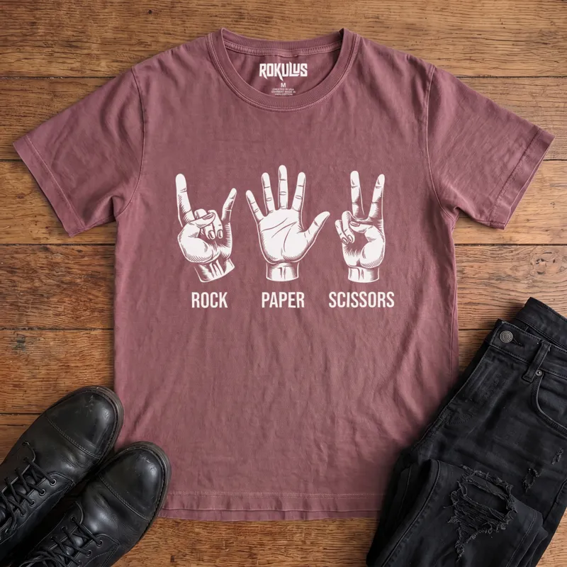 Washed maroon Rokulus Rock Paper Scissors vintage graphic tee laid flat on wood with black boots and jeans, front print showing three hands in vintage engraving, devil horns for rock, flat palm for paper, peace sign for scissors
